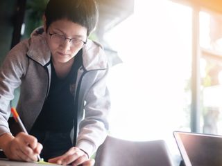 Asian woman writing on a sticky note