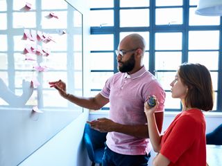 Black man and white woman planning with notes on whiteboard