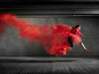Female athlete leaping through red smoke