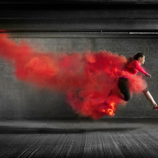 Female athlete leaping through red smoke