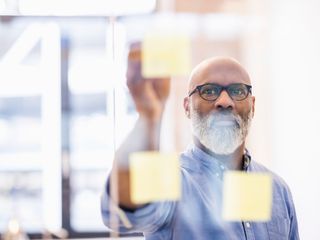 Man taking adhesive note from glass wall in office