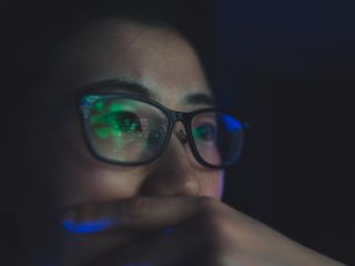 Person with glasses and code reflected on it