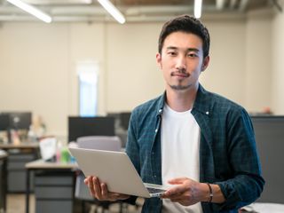 Portrait of asian man holding a computer in an office