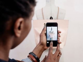 Woman taking a picture with smartphone of a pink leather bag