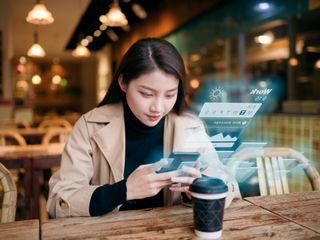 Woman uses mobile phone on virtual visual screen in cafe