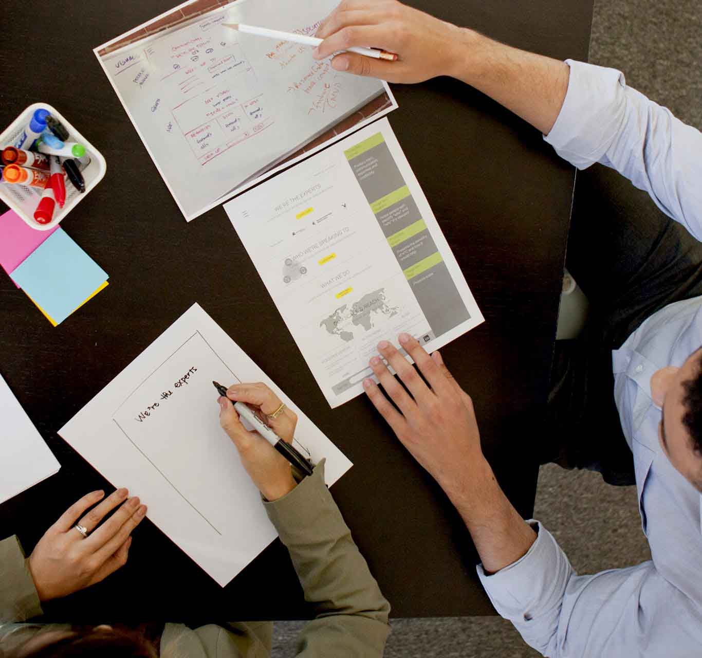 A shot from the top of two people looking at design and writing down notes