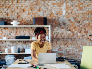 Woman smiling while sitting at table with laptop