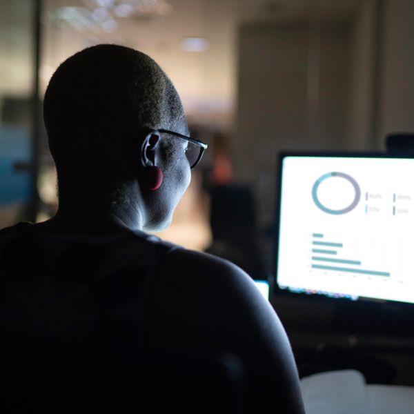 Woman working at night looking at graphs on a computer