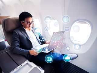 Man on a plain with a computer and worldwide connection technology interface