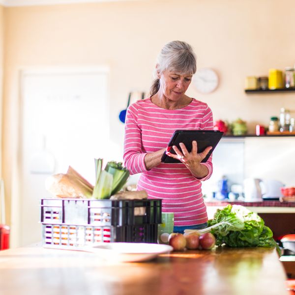 Woman at kitchen checking groceries on tablet