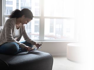 young woman relaxing on a chair while doing online browsing