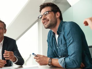 A trio of business individuals collaborating at a table within a professional office environment.
