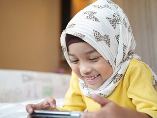Asian Muslim child girl playing a smartphone at home