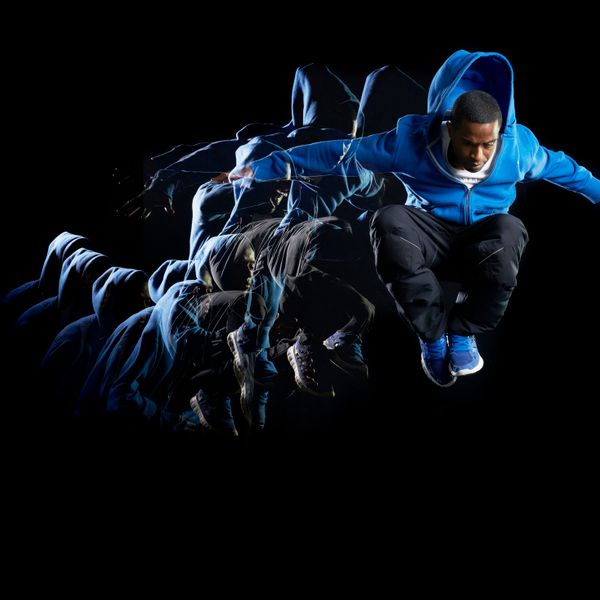 Man with blue jacket jumping in air with multiple strobe on a dark background