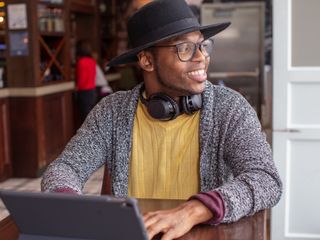 Man with digital tablet in airport bar smiles as he looks out the window