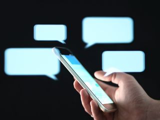 Text messages on cellphone screen with abstract hologram speech bubbles