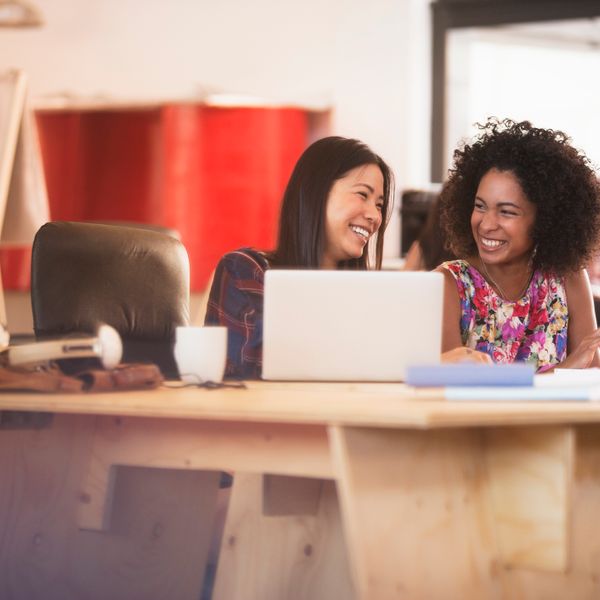 Two women smiling and working on a conference table