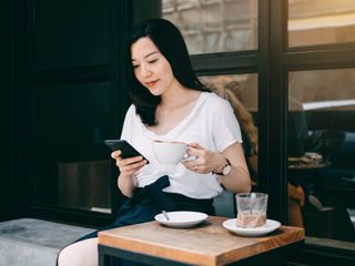 Woman in a cafe drinking coffee and using a mobile phone