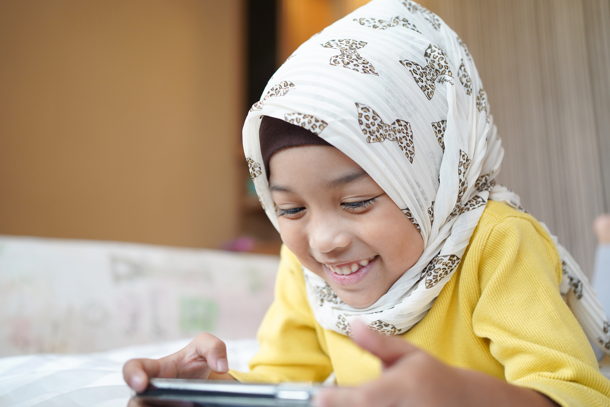 Asian Muslim child girl playing a smartphone at home