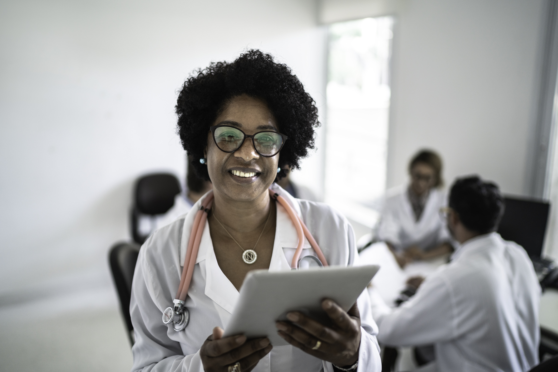Female doctor using a digital tablet with doctor's meeting on background